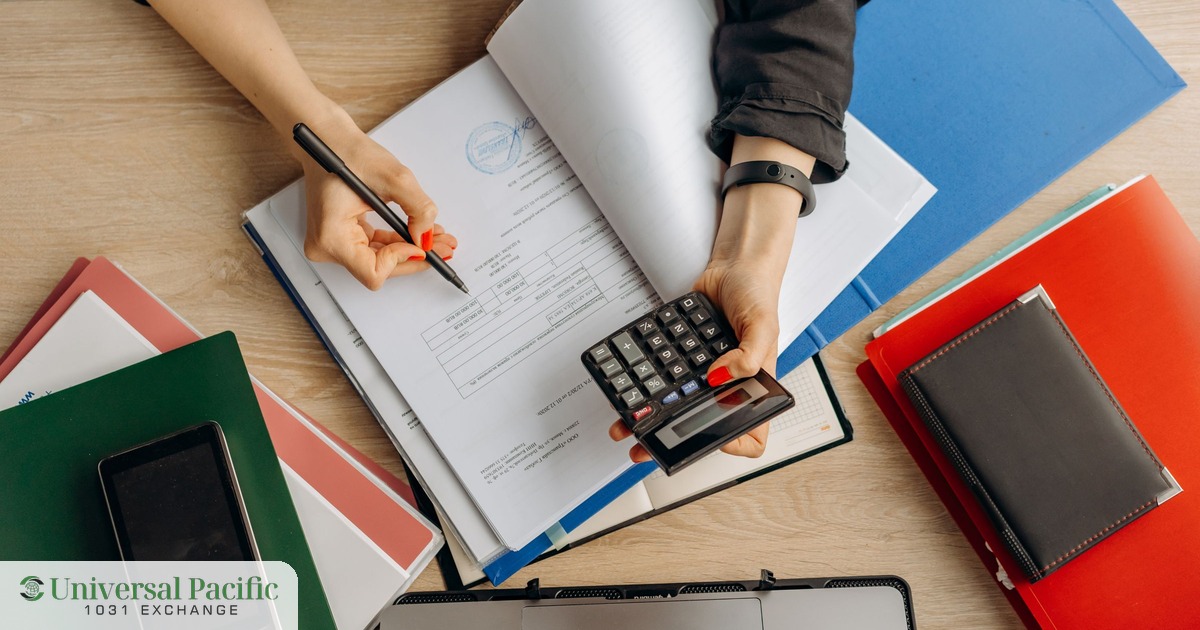 A person calculating federal capital gains tax with a calculator, documents, and a laptop
